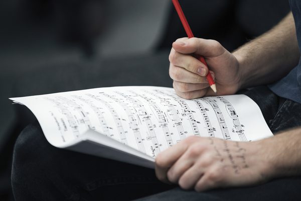 Close up on hands as they write on sheet music.