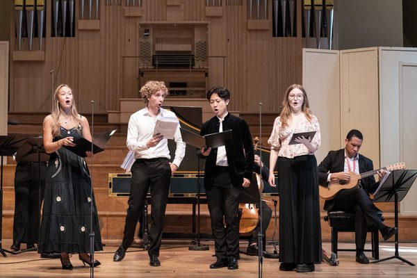 A pianist plays in the background while an audience watched in the foreground.