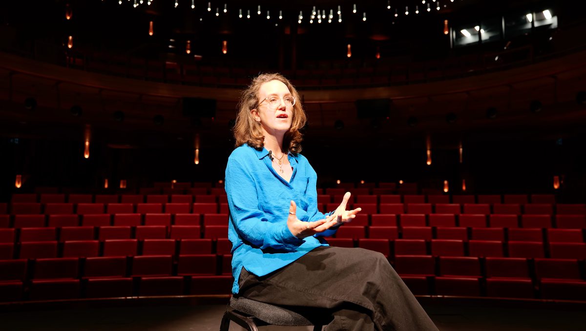 Helen Grime sits on stage in an auditorium, talking to an interviewer off-camera.