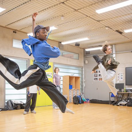 Two young performers in rehearsal, jumping and dancing.