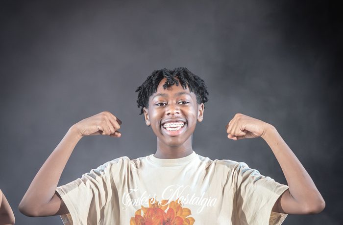 A young performer flexes their arm muscles, mid-performance.