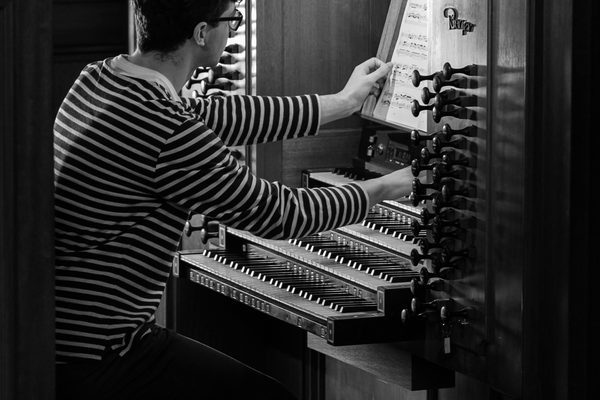 Close up of an organ student adjusting the drawknobs in an organ (black and white).