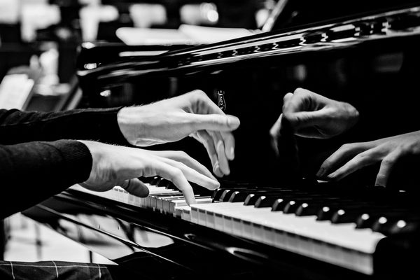 A wide shot of hands on a piano keyboard.
