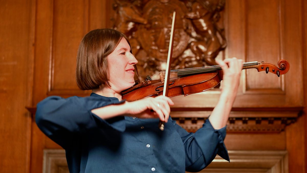 Side view of a violin teacher mid-solo.