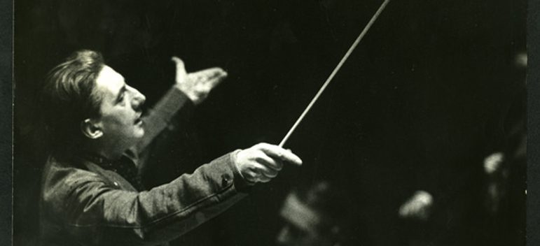 Scanned black and white image of the composer Barbirolli from the side, raising arms and a clenched baton.