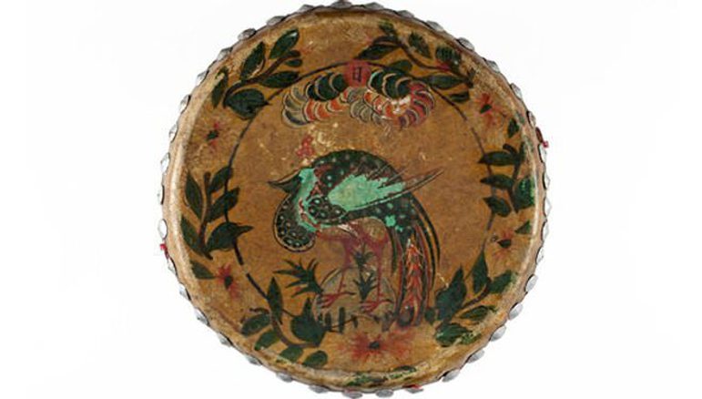 A tambourine with a multicoloured peacock illustration painted on the skin.