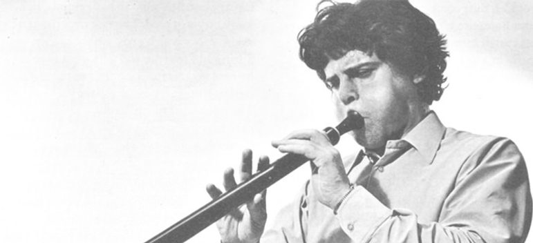 Scanned black and white image of a musician blowing into a bass recorder.