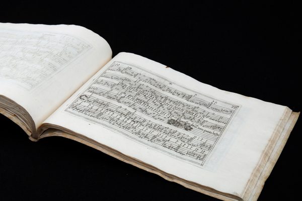 A book of sheet music open on a page with hand-written notes.