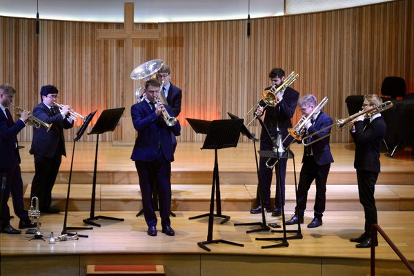 A group of brass players performing on a wooden stage.