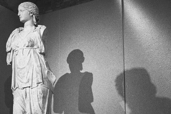 A sculpted bust casts a strong shadow against a light wall.