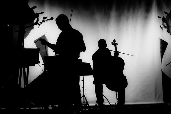 Black and white silhouettes of a pianist and a cellist on a stage.