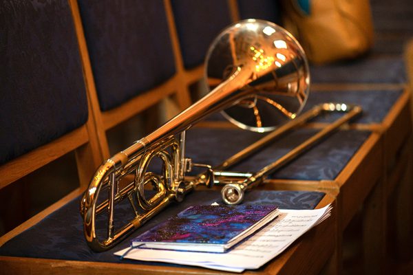 A trombone sits alongside a notebook across a row of chairs.