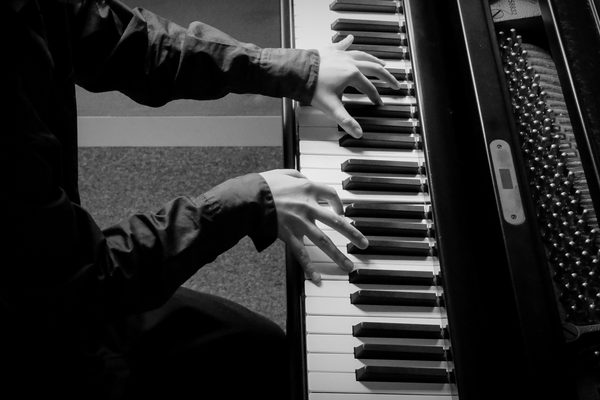 Two hands on a piano keyboard.