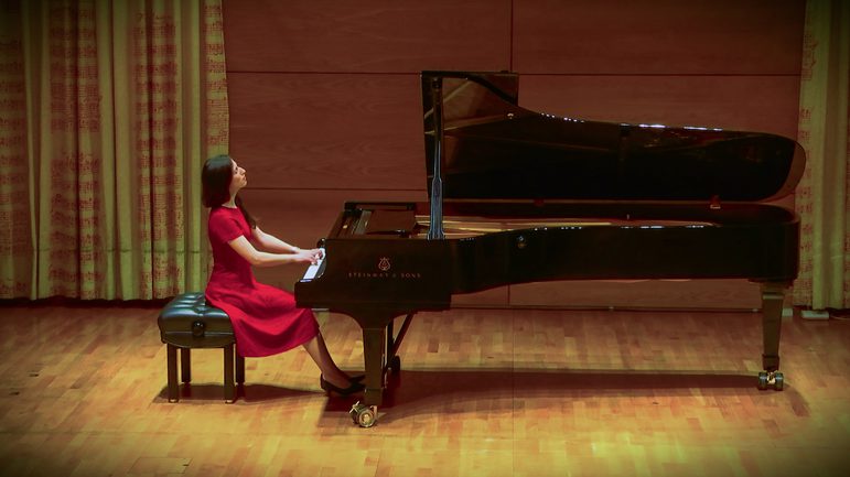 A sperson playing a concert piano.