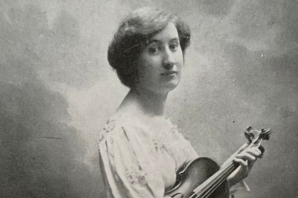 An old black and white photo of a woman in profile, holding a violin.