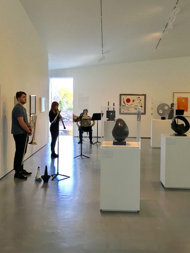 Onlookers study sculptures at an art exhibition.