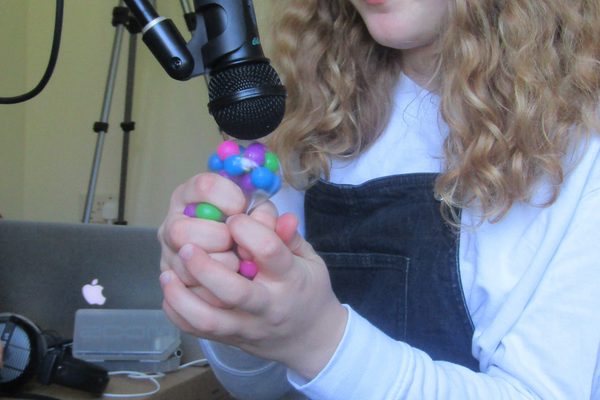 A young participant squeezes a sensory toy near a microphone.
