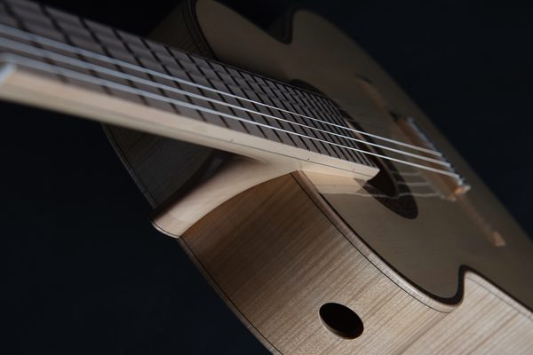 A top down view of a light wood acoustic guitar on a dark background.