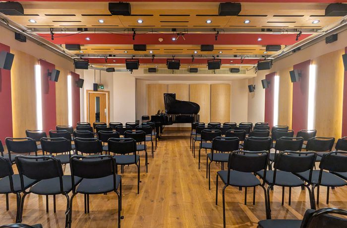 A concert room with a small seating area and a grand piano.