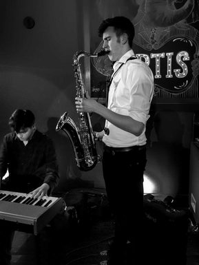 A saxophone player accompanied by a keyboard player.