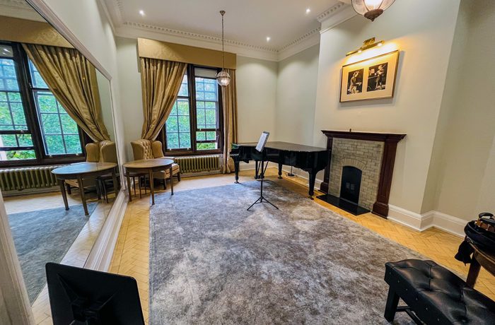 A teaching room with a piano and a fireplace.