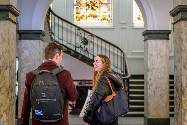 Student smile and talk in the Academy foyer.