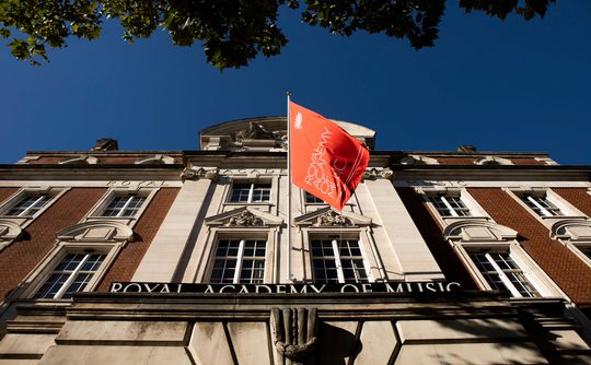 The Academy flag flying against a clear sky at the front of the main building.