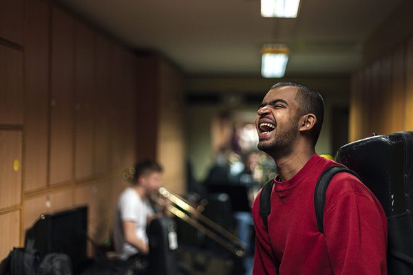 A student stands in a hallway, smiling.