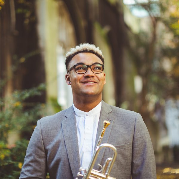 Aaron Akugbo smiles, looking skyward in an outdoor setting.