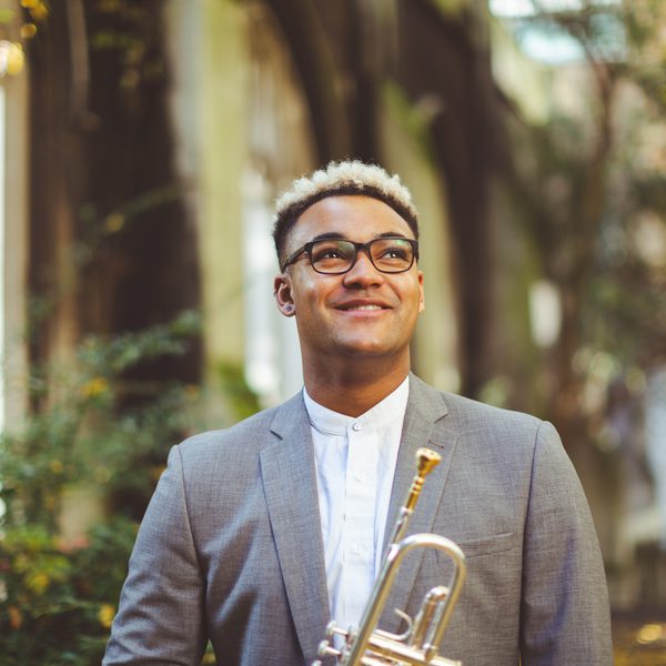 Aaron Akugbo smiles, looking skyward in an outdoor setting.