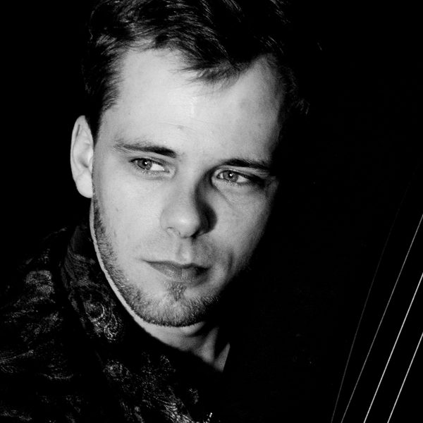 Stylised monochromatic portrait headshot of Alexander Boldachev holding a harp staring off camera.