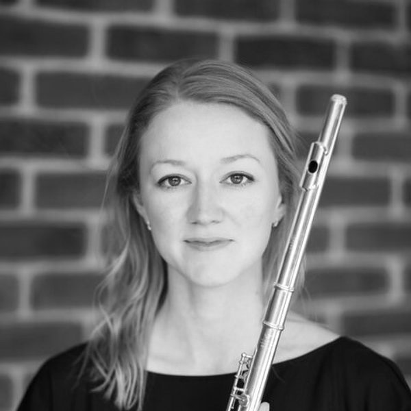 Amy Yule smiles to camera, holding a flute.