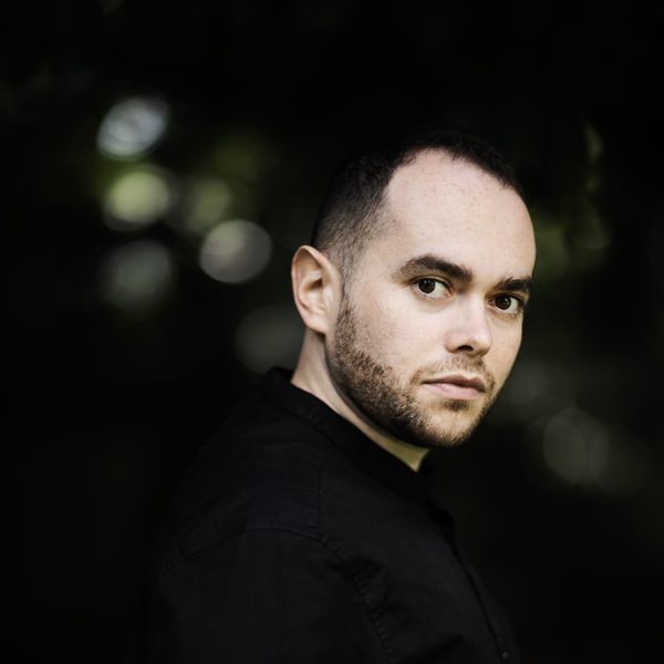 Portrait of conductor Ben Glassberg outside, facing camera.