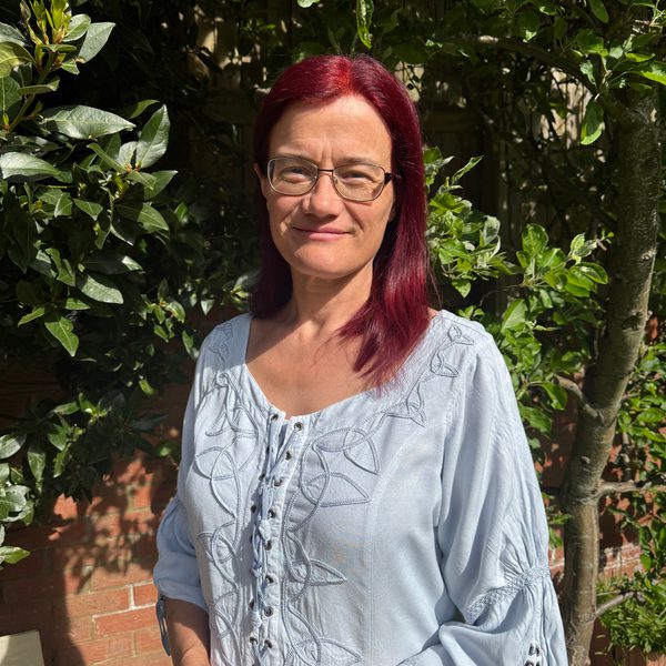 Briony Cox-Williams stands in a sunlit garden and looks to camera