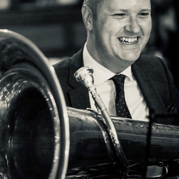 Carl Woodcroft holds a tuba, smiling