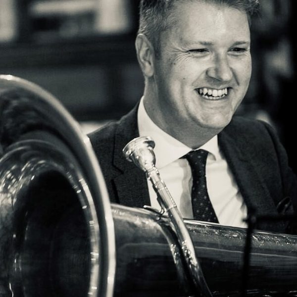 Carl Woodcroft holds a tuba, smiling.