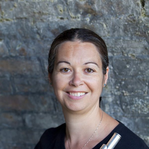 Carla Rees smiles to camera holding a flute.