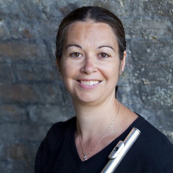 Carla Rees smiles to camera holding a flute