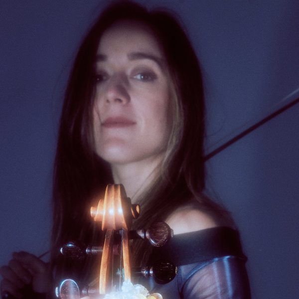 Headshot of Catriona Price holding a violin, with bow draped slung over the shoulder.