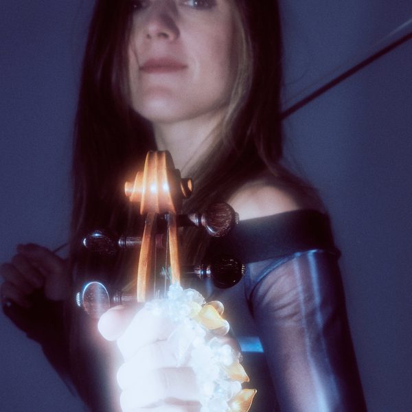 Headshot of Catriona Price holding a violin, with bow draped slung over the shoulder