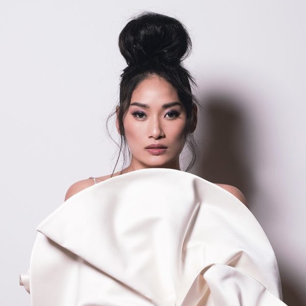 Chloe Flower looks to camera, in front of a fanned piece of fabric.