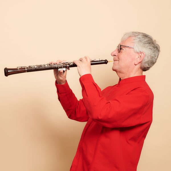 Side image of an oboe player in a red sweater.