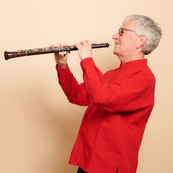 Side image of an oboe player in a red sweater