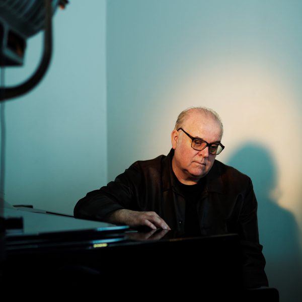Craig Armstrong spotlit in a corner of a room.