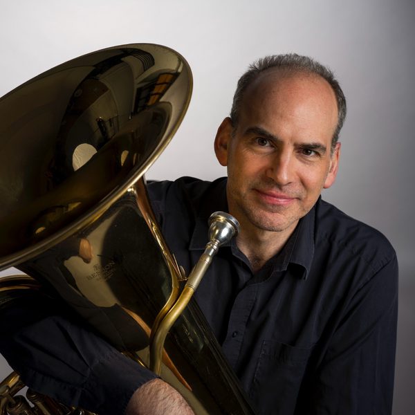 A man holding a tuba and looking to camera.
