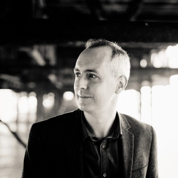Side portrait of David Gorton in a well-lit outdoor space.
