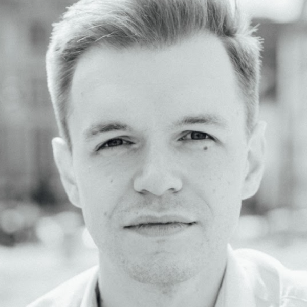 Portrait of David Gray looking to camera against a blurry outdoor setting (black and white)