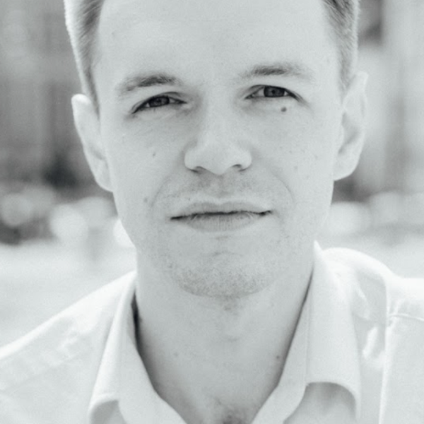 Portrait of David Gray looking to camera against a blurry outdoor setting (black and white)