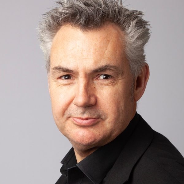 Dominic Hackett poses for photo against a grey background.