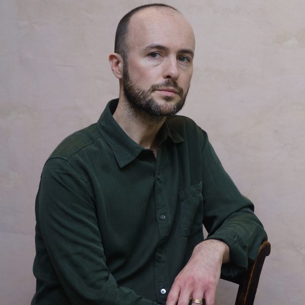 Edmund Finnis leans elbow on chair while looking to camera